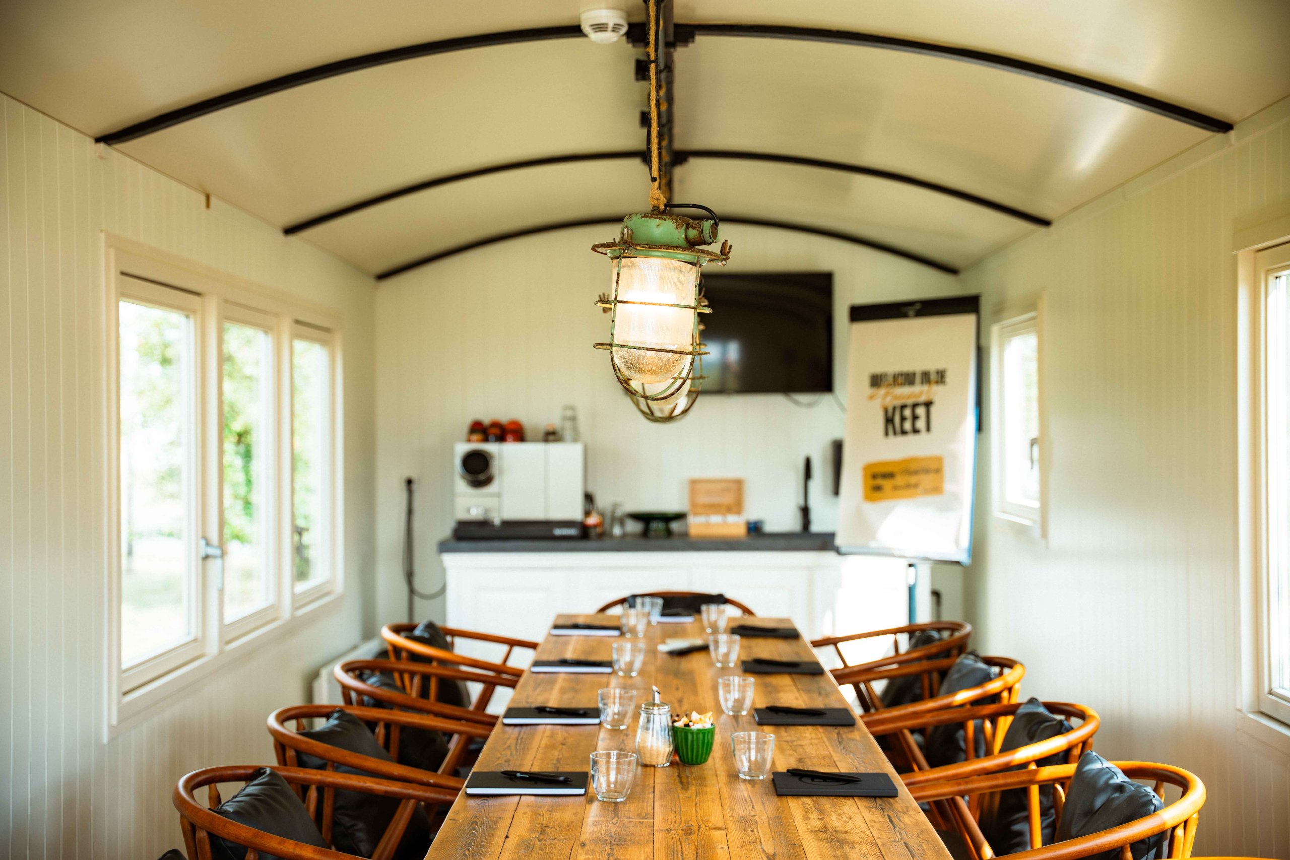 Vergadertafel in een keet met gewelfd plafond en ramen bij Brasserie Polderfabriek in Leiderdorp